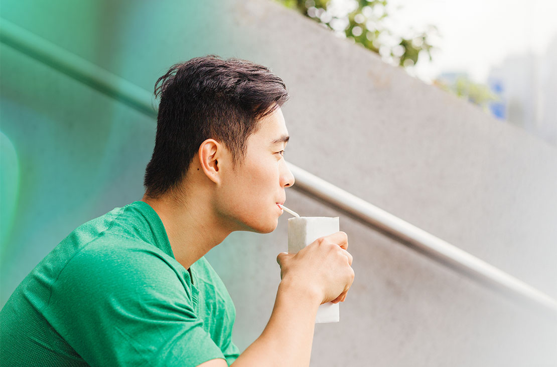 Active Asian man drinking from packet drink