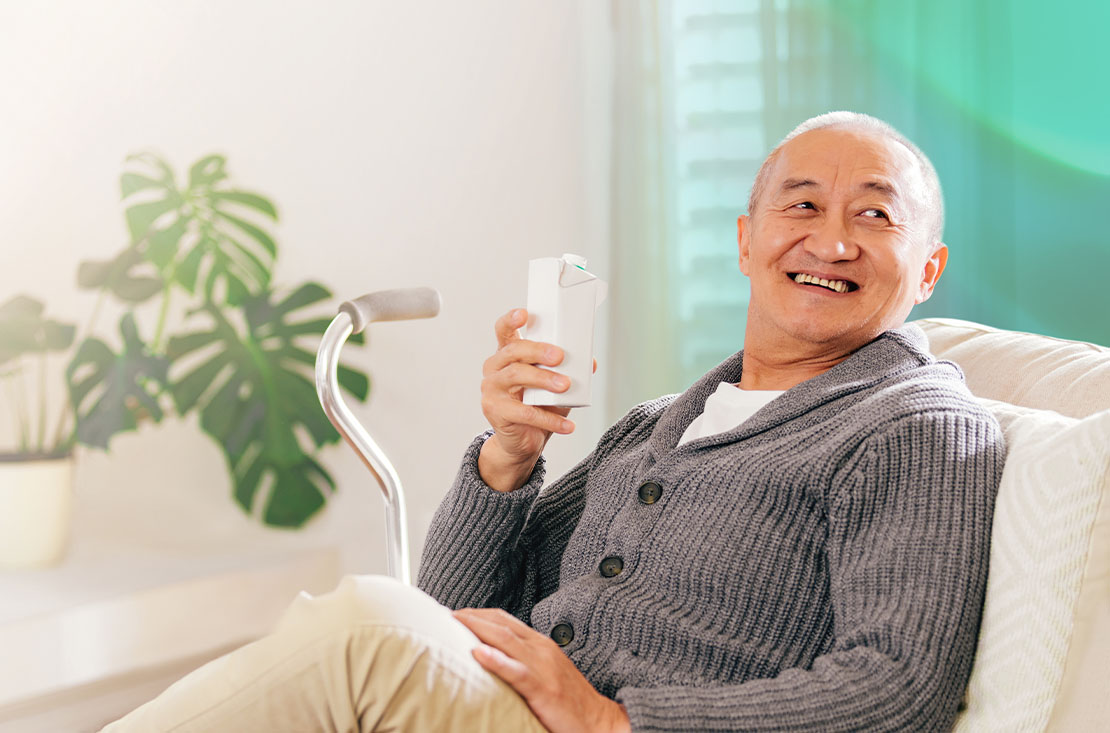 Asian elderly patient holding a carton of drink